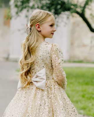 Když se světla rozsvítí, třpyt ožívá. Naše zlaté šaty s mašlí jsou snem každé malé princezny – ideální pro vánoční focení...